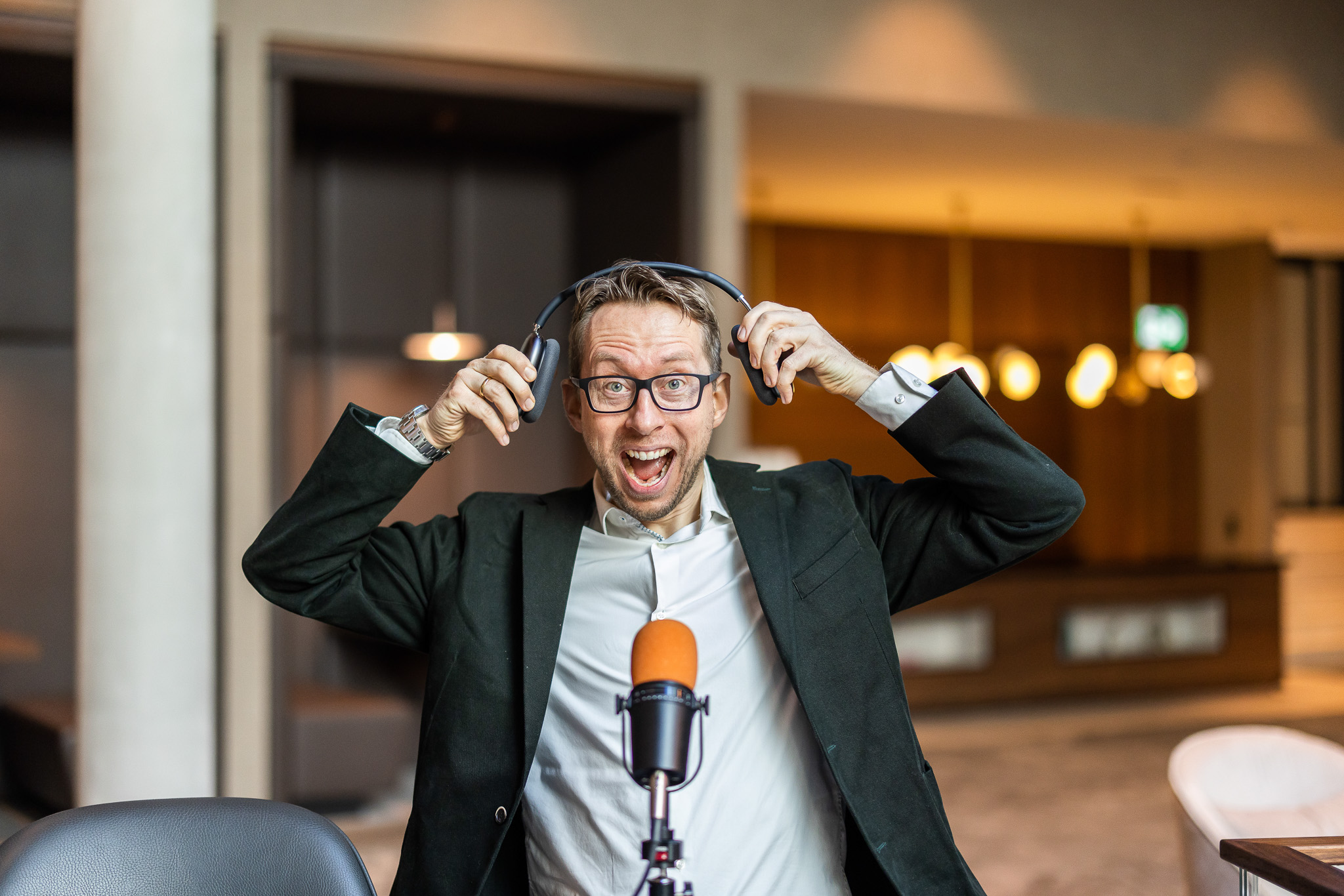 Daniel Schwenger putting on headphones behind a podcast microphone
