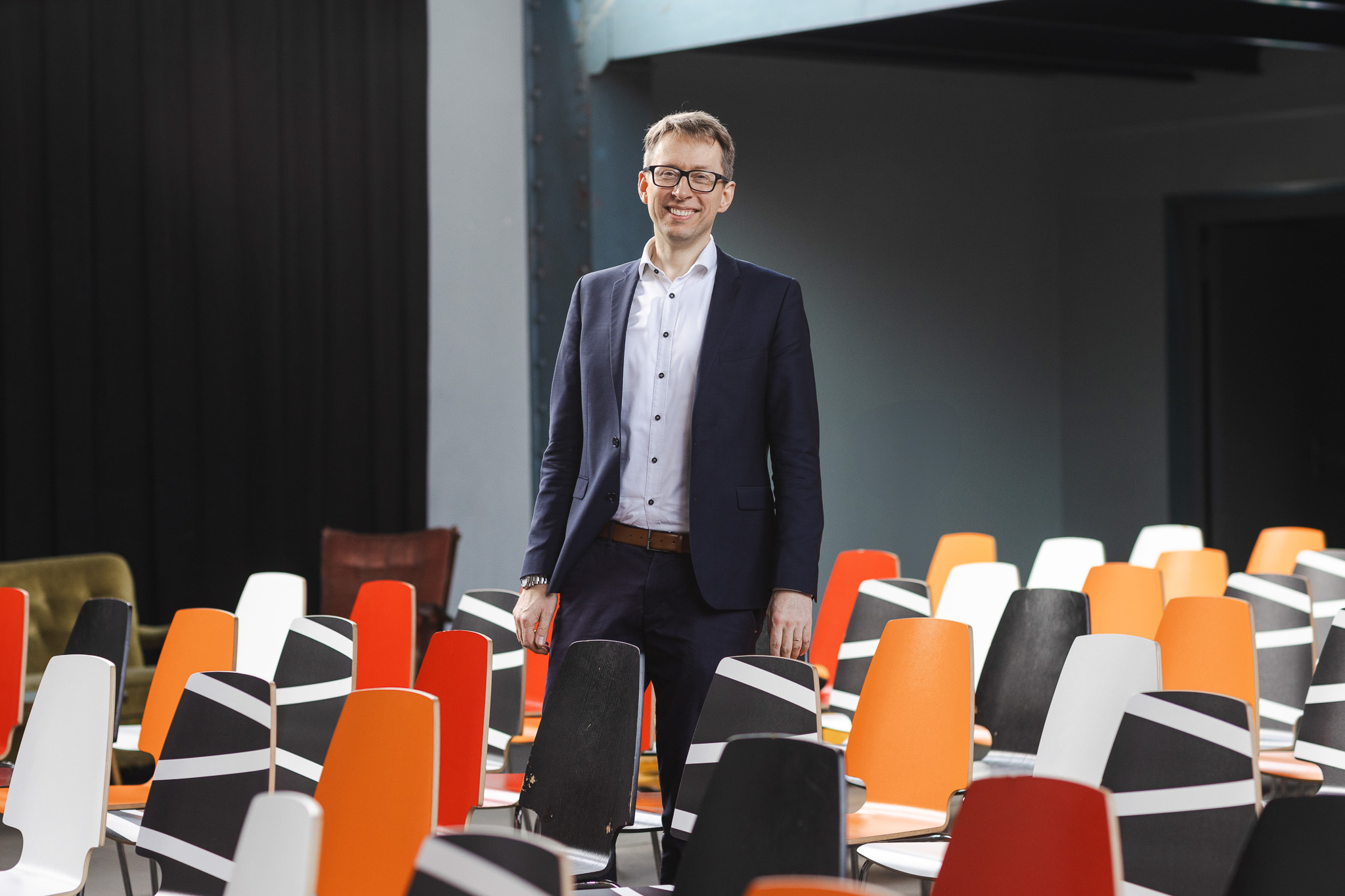 Daniel Schwenger standing among colourful chairs in an event venue