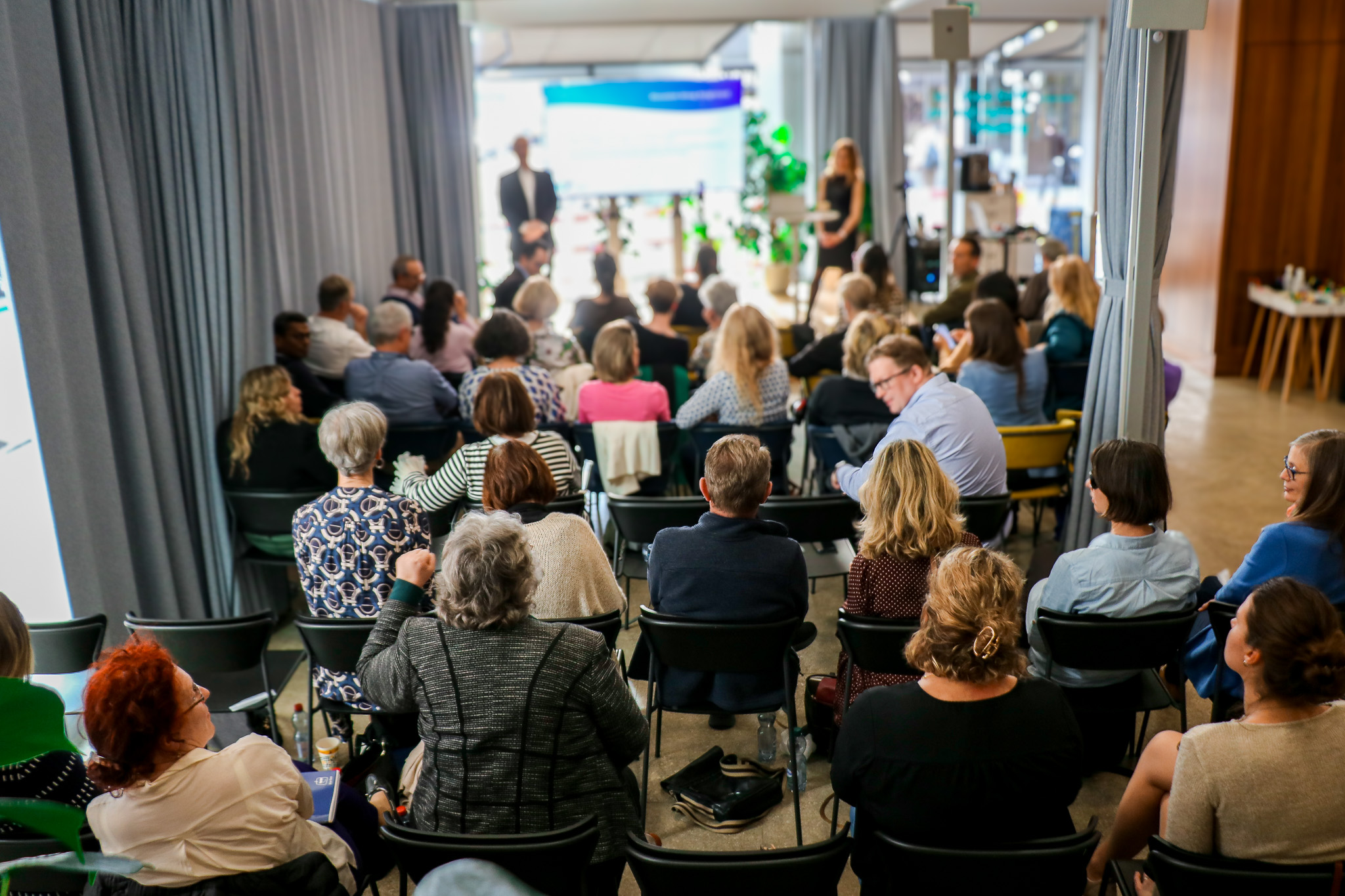 Audience seated in rows watching two speakers